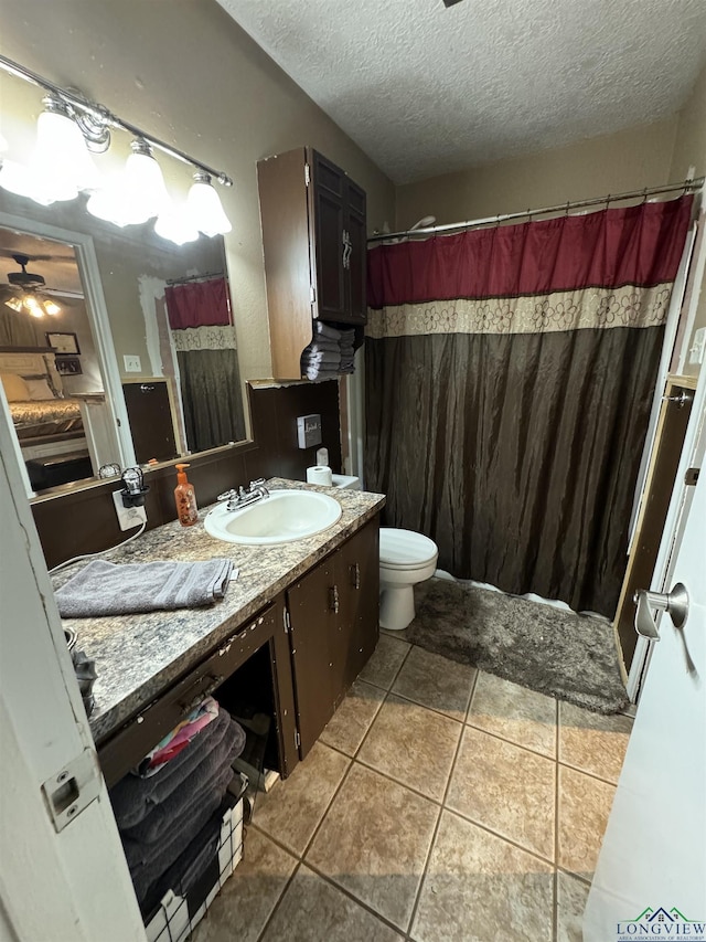 bathroom with ceiling fan, tile patterned flooring, a textured ceiling, toilet, and vanity