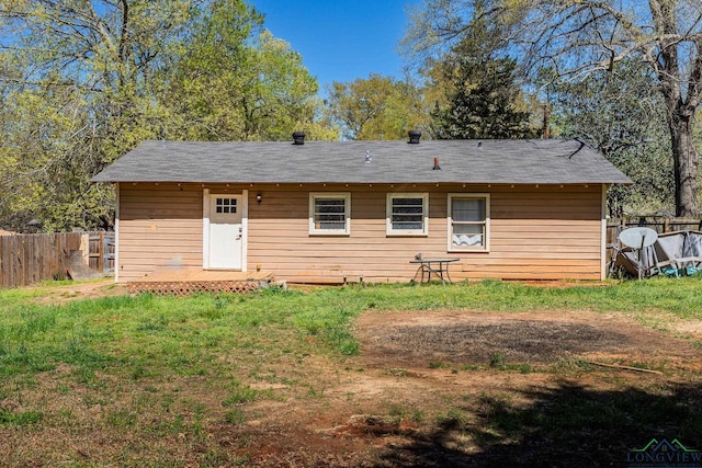back of property featuring fence and a yard