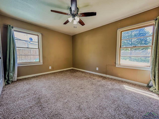carpeted empty room with baseboards, ceiling fan, and a wealth of natural light