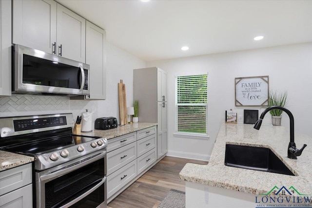 299 Southshore Dr, Lone Star, TX 75668 - kitchen with stainless steel appliances, a sink, wood finished floors, backsplash, and light stone countertops