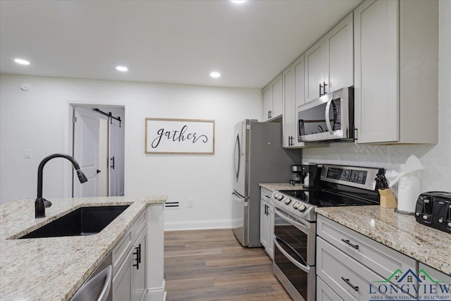 299 Southshore Dr, Lone Star, TX 75668 - kitchen with stainless steel appliances, a sink, dark wood-type flooring, decorative backsplash, and light stone countertops