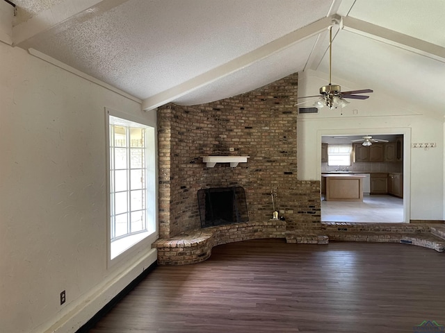 unfurnished living room with a wealth of natural light, lofted ceiling with beams, wood-type flooring, and a textured ceiling