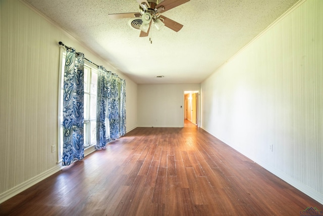 empty room featuring a textured ceiling, dark hardwood / wood-style floors, ceiling fan, and crown molding