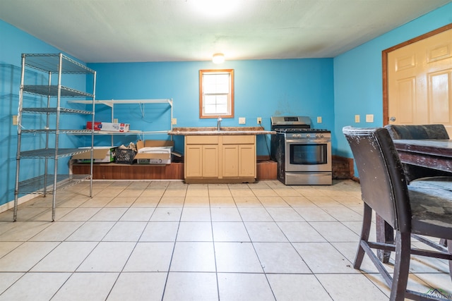 kitchen featuring light tile patterned flooring, light brown cabinetry, gas stove, and sink