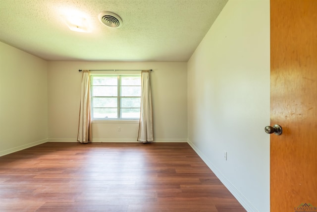 empty room with wood-type flooring and a textured ceiling