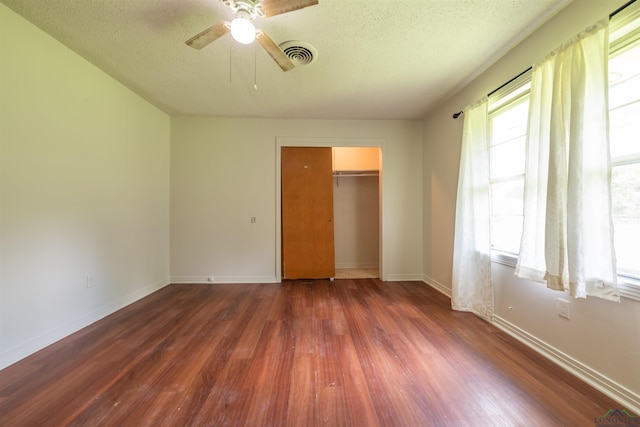 unfurnished bedroom with multiple windows, a closet, dark hardwood / wood-style floors, and ceiling fan