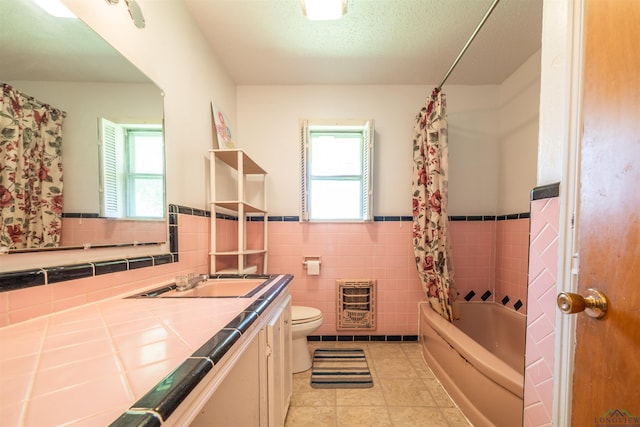 full bathroom featuring shower / bath combination with curtain, vanity, heating unit, tile walls, and toilet