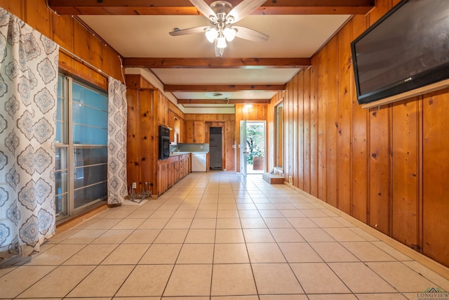 unfurnished living room with beamed ceiling, ceiling fan, light tile patterned flooring, and wooden walls