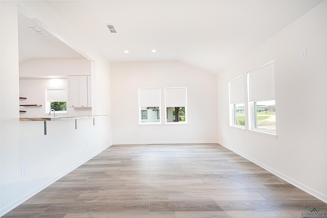 unfurnished living room with lofted ceiling, sink, and light hardwood / wood-style flooring