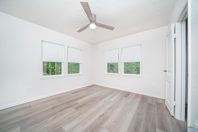 empty room featuring a textured ceiling, light wood-type flooring, and ceiling fan