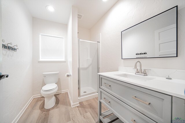 bathroom with hardwood / wood-style floors, vanity, toilet, and a shower with shower door