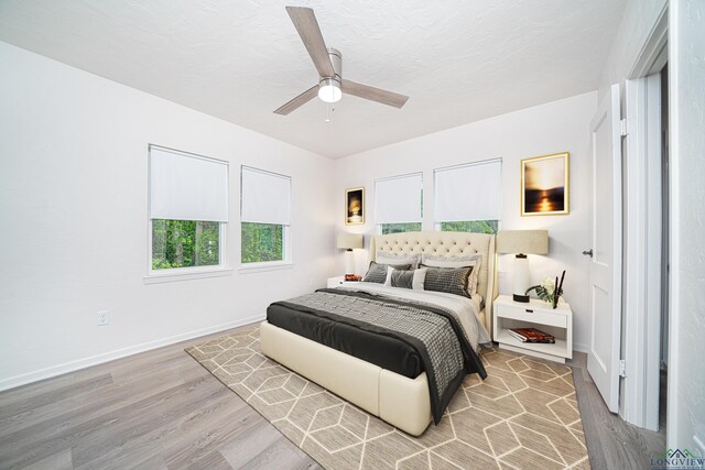 bedroom with ceiling fan, a textured ceiling, and light hardwood / wood-style flooring