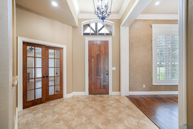 entryway with french doors, an inviting chandelier, light hardwood / wood-style flooring, and crown molding