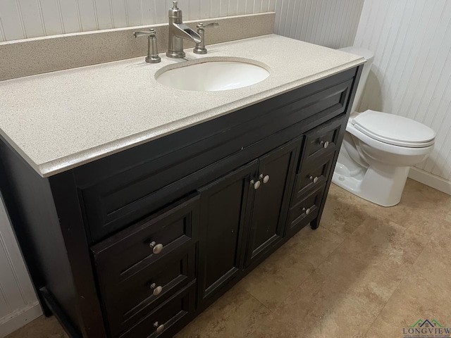 bathroom with vanity, toilet, and wooden walls