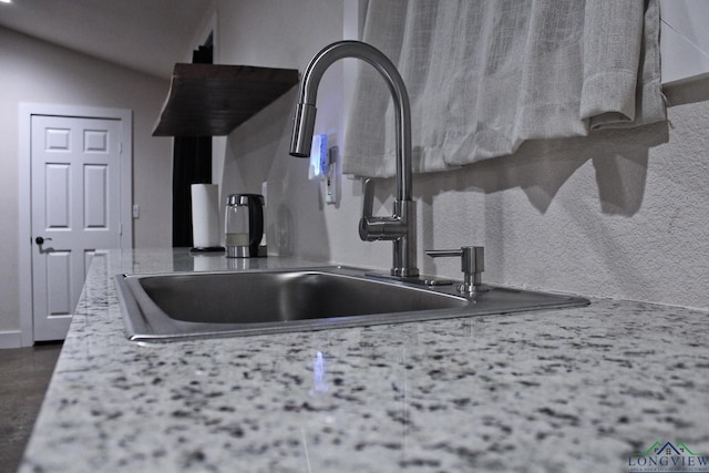 room details featuring light stone countertops and sink