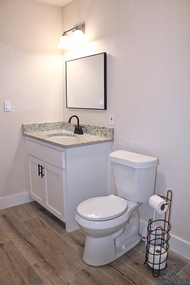 bathroom with vanity, toilet, and hardwood / wood-style floors