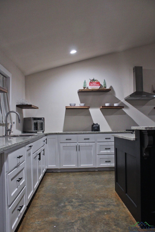 kitchen featuring white cabinetry, light stone countertops, sink, and wall chimney range hood