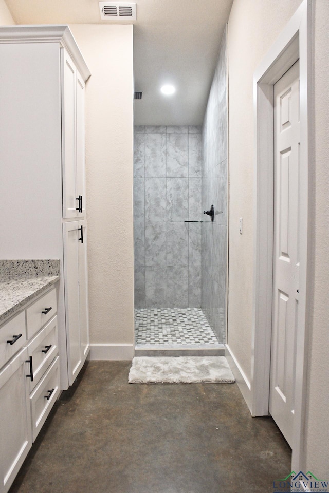 bathroom with vanity, concrete flooring, and tiled shower