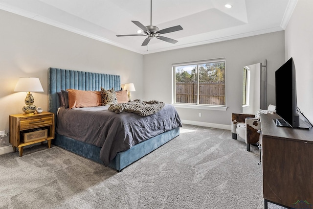 bedroom featuring baseboards, ornamental molding, carpet floors, a raised ceiling, and a ceiling fan