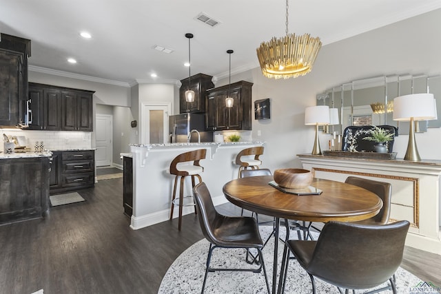 dining space with dark wood-style floors, baseboards, visible vents, an inviting chandelier, and ornamental molding