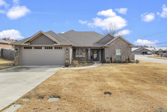 view of front of home with driveway, fence, roof with shingles, a garage, and brick siding