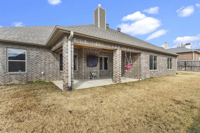 rear view of property with ceiling fan, a patio, brick siding, and a chimney