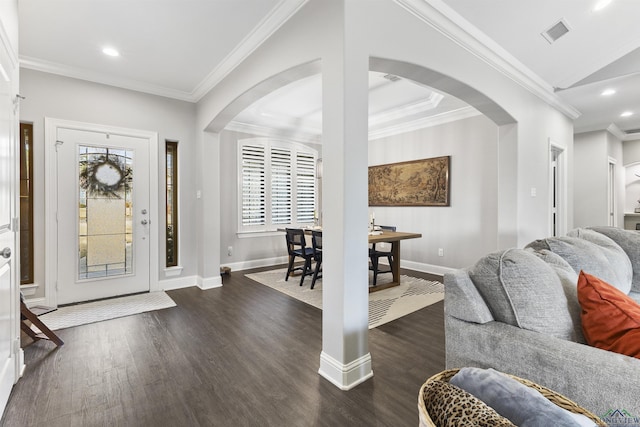 entryway with baseboards, visible vents, dark wood finished floors, arched walkways, and crown molding