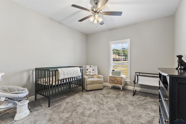 carpeted bedroom with a nursery area, a ceiling fan, and baseboards