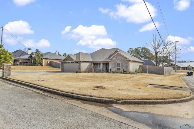 view of front of home with an attached garage, fence, brick siding, and driveway