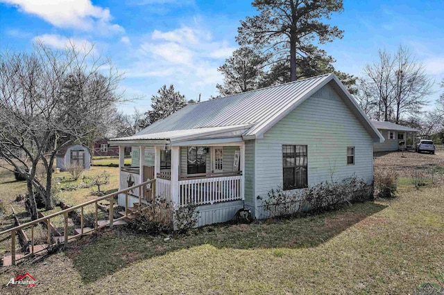 view of front of house featuring covered porch, a storage shed, a front lawn, and an outbuilding