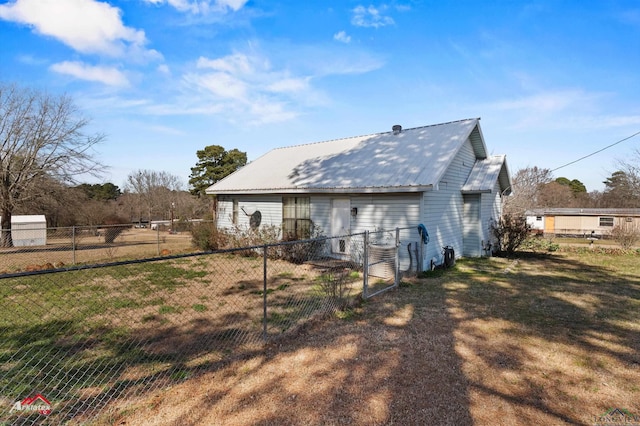 rear view of house with a yard, metal roof, and fence