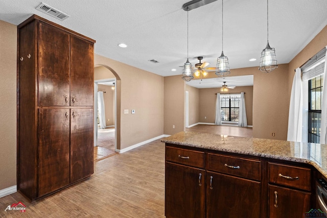 kitchen featuring arched walkways, light wood-style flooring, visible vents, open floor plan, and hanging light fixtures