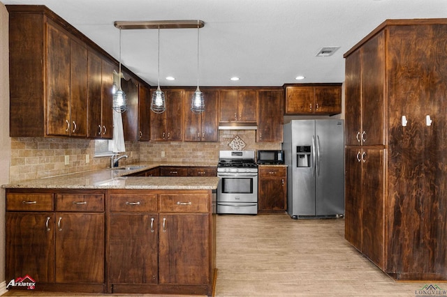 kitchen featuring light stone counters, pendant lighting, visible vents, appliances with stainless steel finishes, and a sink