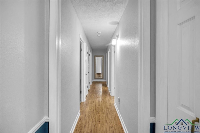 1611 Springdale St, Longview, TX 75604 - hallway featuring light wood-style flooring, a textured ceiling, a textured wall, and baseboards