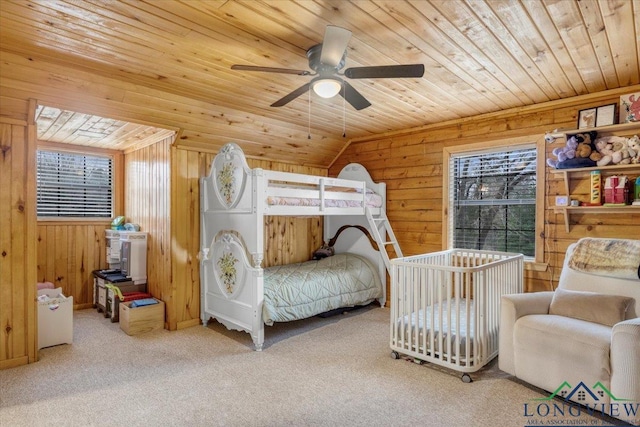 carpeted bedroom featuring wooden walls, wooden ceiling, ceiling fan, and vaulted ceiling