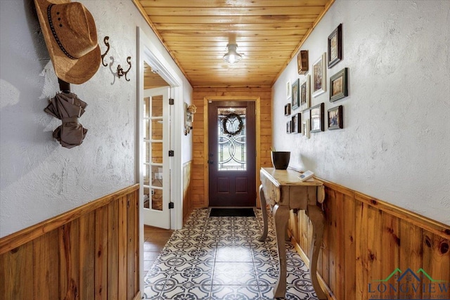 entryway with wood ceiling, wooden walls, and light tile patterned floors