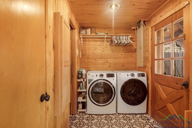 laundry area with washer and clothes dryer, light tile patterned floors, wood ceiling, and wooden walls