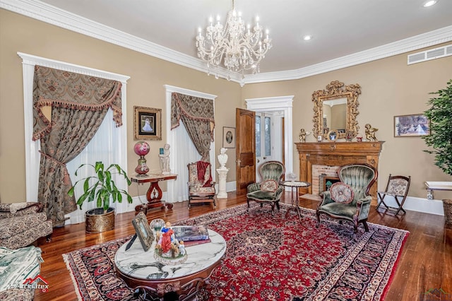 sitting room with dark hardwood / wood-style floors, crown molding, a fireplace, and a chandelier