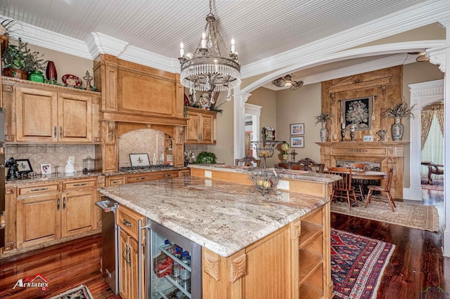 kitchen with a center island, decorative backsplash, ornate columns, dark hardwood / wood-style flooring, and beverage cooler