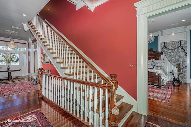 staircase with wood-type flooring and crown molding