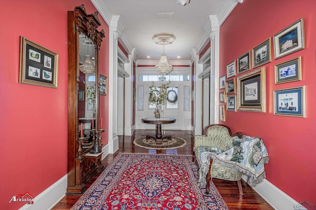 corridor featuring hardwood / wood-style flooring, crown molding, and decorative columns