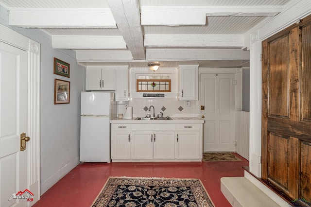 kitchen featuring decorative backsplash, sink, white refrigerator, beamed ceiling, and white cabinetry