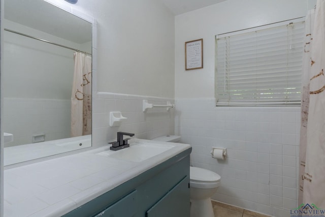 bathroom with tile patterned floors, vanity, toilet, and tile walls