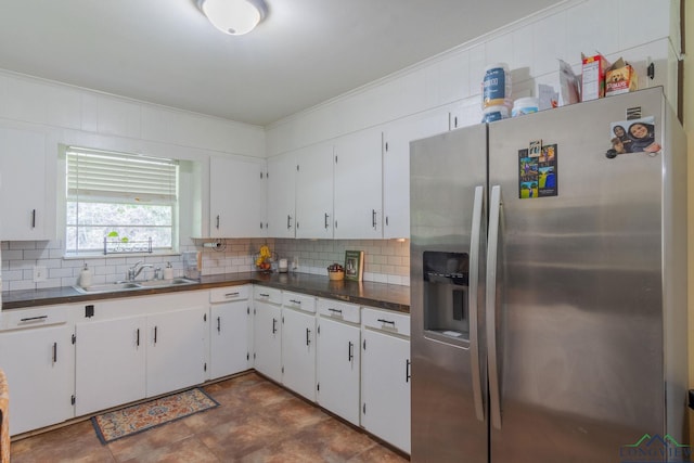 kitchen with stainless steel refrigerator with ice dispenser, backsplash, ornamental molding, sink, and white cabinets