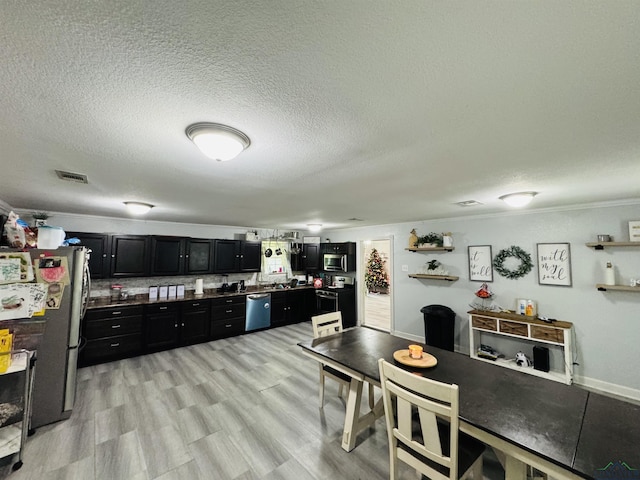 kitchen featuring light hardwood / wood-style flooring, stainless steel appliances, a textured ceiling, and ornamental molding