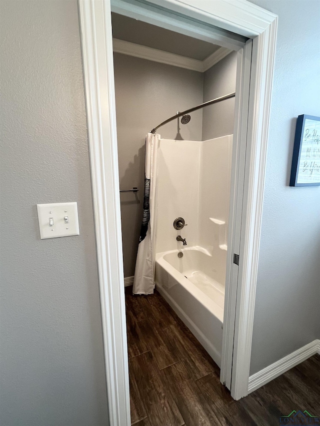 full bathroom with wood finished floors, shower / bath combo with shower curtain, and baseboards