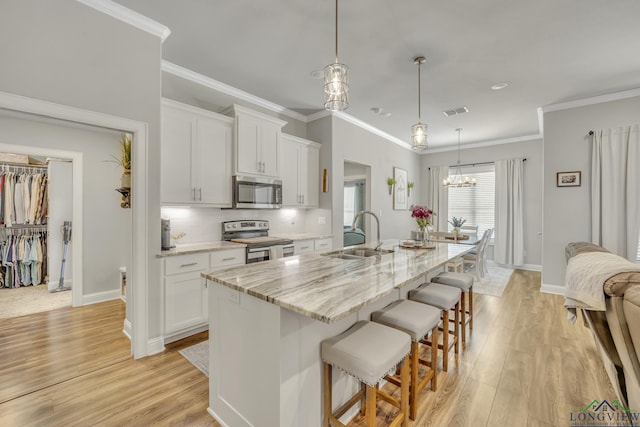 17182 Ironwood Dr, Flint, TX 75762 - kitchen featuring stainless steel appliances, a breakfast bar, white cabinets, light wood-style flooring, and ornamental molding