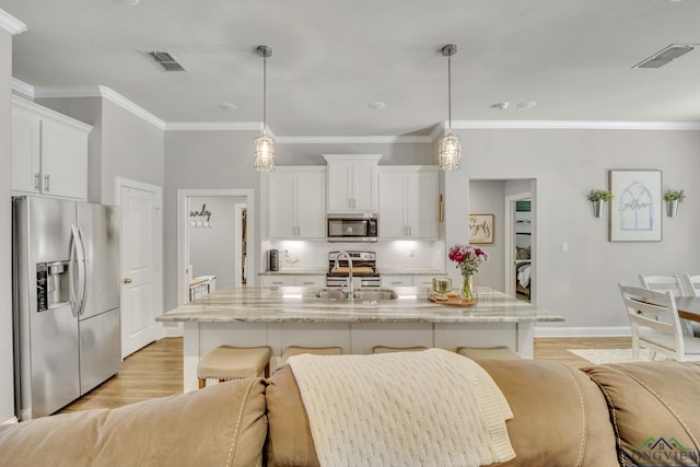 17182 Ironwood Dr, Flint, TX 75762 - kitchen with appliances with stainless steel finishes, a kitchen breakfast bar, white cabinets, ornamental molding, and light wood finished floors