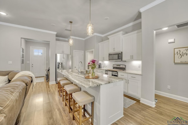 17182 Ironwood Dr, Flint, TX 75762 - kitchen with appliances with stainless steel finishes, a breakfast bar area, light wood finished floors, white cabinetry, and ornamental molding