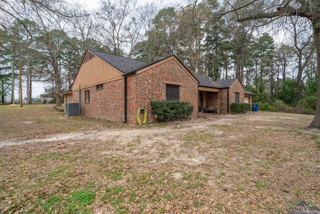 view of side of property with cooling unit, brick siding, and an attached garage